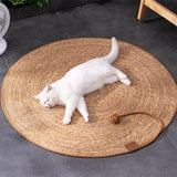 White cat lying on a round woven mat with a wooden base on a dark tiled floor.